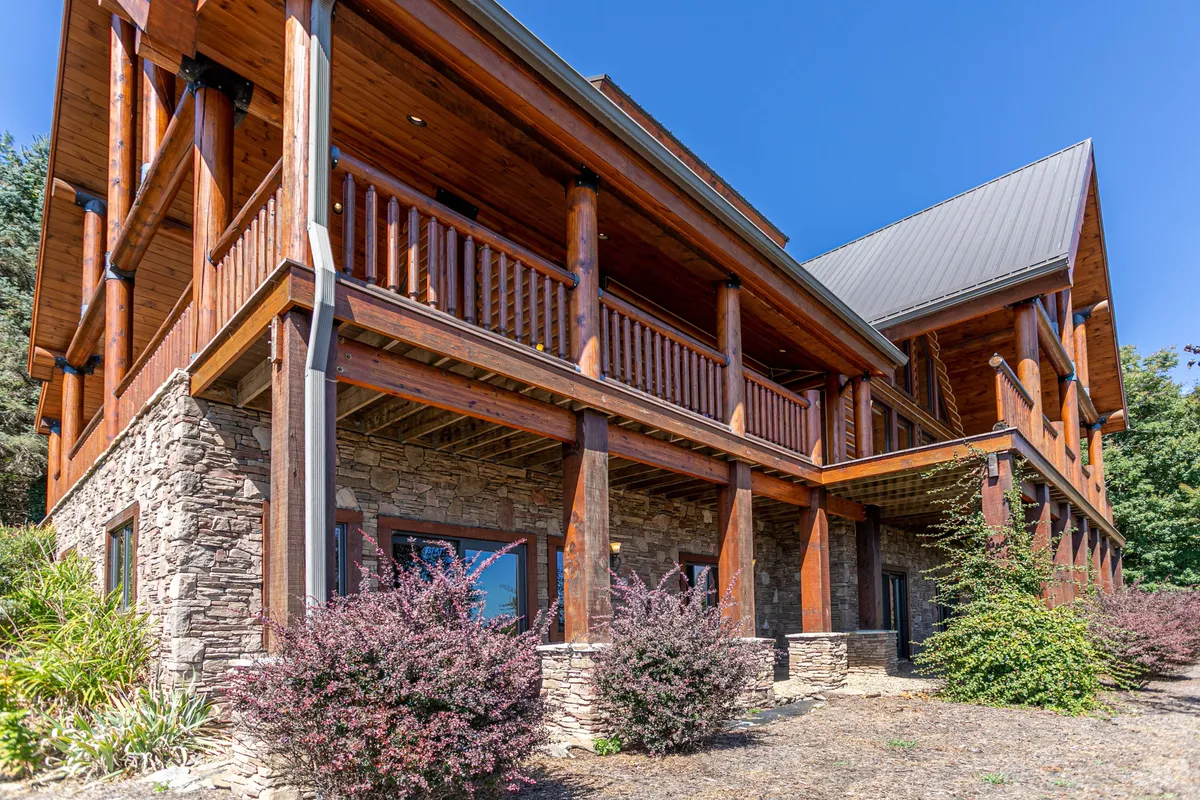 A view of the lodge’s wooden balcony and stone facade, with a landscaped garden below. The balcony is an inviting space for fresh air breaks, informal discussions, and moments of solitude amidst nature.