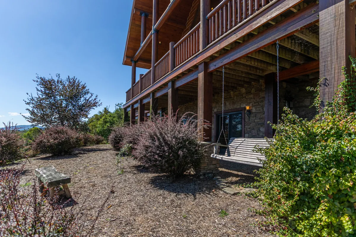 A tranquil porch with a swing bench, landscaped bushes, and sturdy wooden columns. The swing offers a restful spot for morning coffee or a peaceful place to unwind after a day exploring Boone and its attractions.
