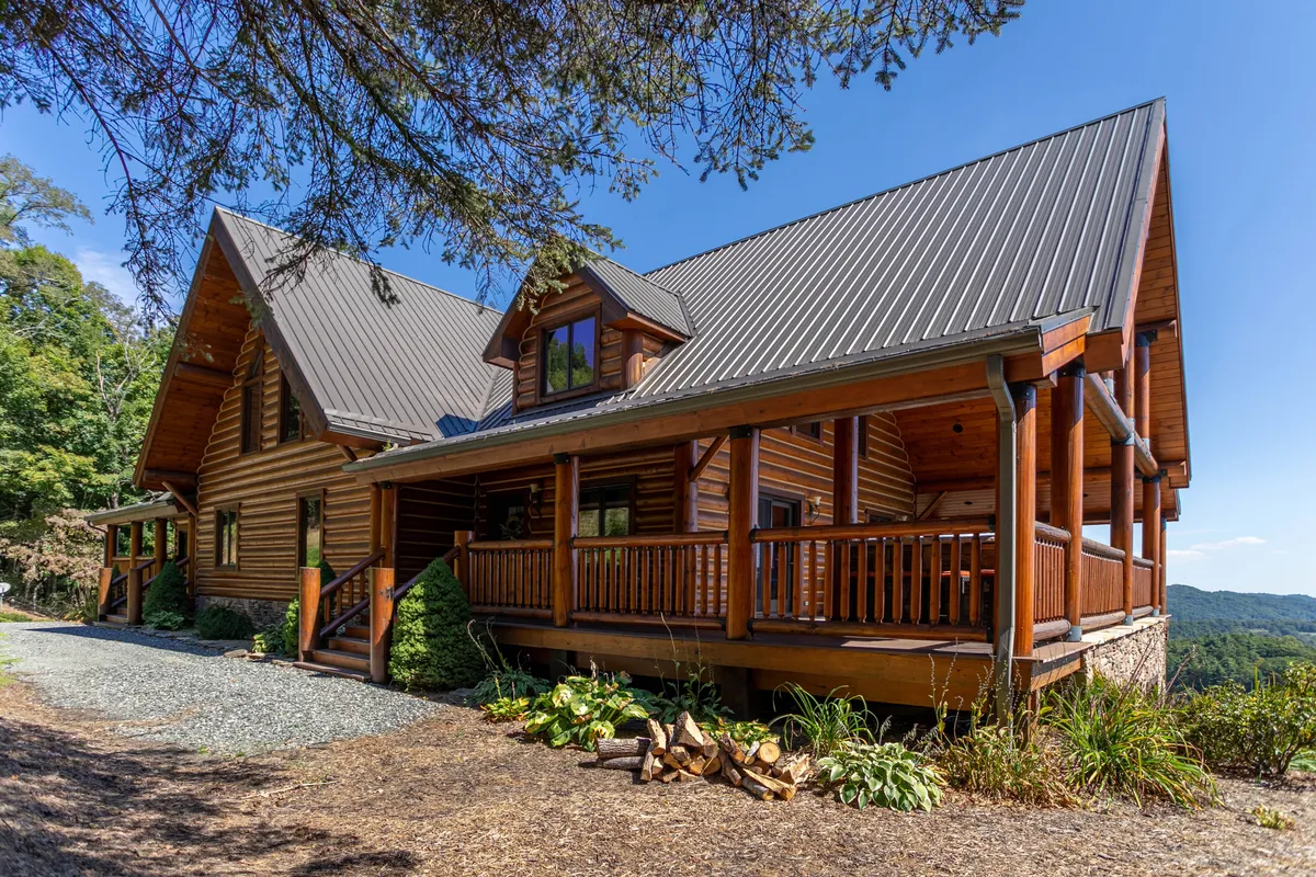 A welcoming wooden porch and log cabin structure surrounded by lush greenery. The spacious porch provides an inviting space to relax after a day of mountain adventures, with ample seating for groups to gather, share stories, or prepare for the next outing.