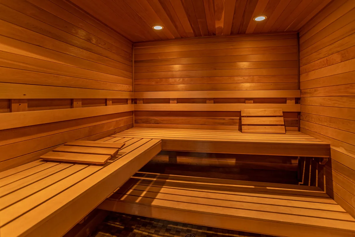 A serene, wood-paneled sauna featuring smooth wooden benches and calming recessed lighting. The tranquil atmosphere signals a perfect post-adventure retreat, ideal for relaxation and recovery after a day of hiking, skiing, or golfing.